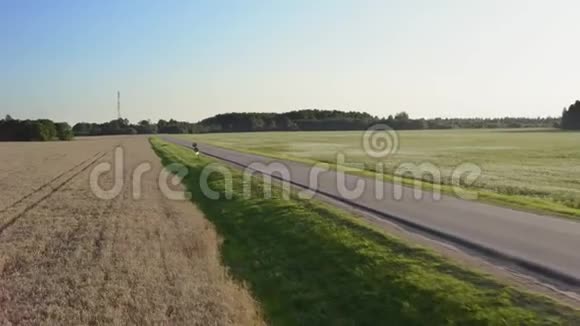 农业方面的直线道路人骑摩托车在夕阳下经过现场空中观景4K视频的预览图