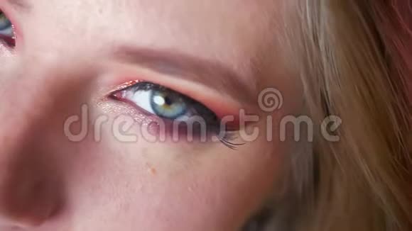 迷人的女性蓝眼睛化妆粉红色阴影和金色眼线看相机视频的预览图