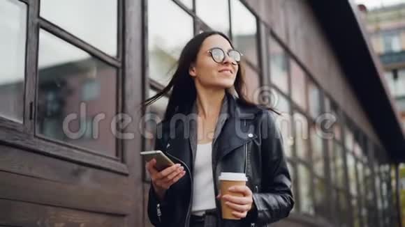 现代都市黑发美女独自走着拿着咖啡用的慢动作视频的预览图