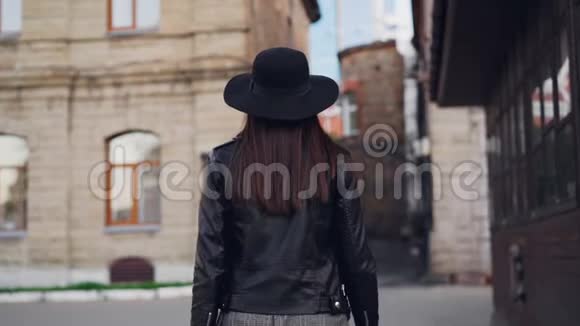 慢镜头肖像快乐的年轻女士留着长长的黑发戴着眼镜和帽子带着购物袋走路然后视频的预览图