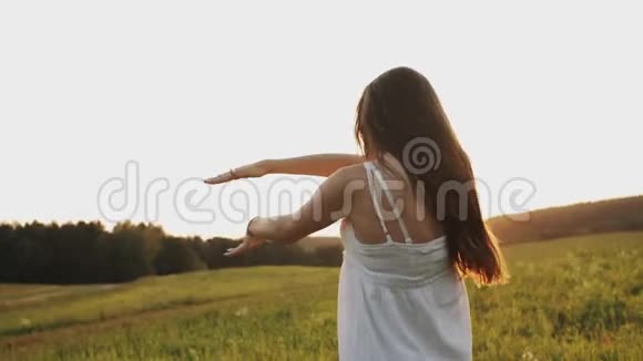 快乐的女人心情愉快在夕阳的照耀下在田野里笑着跳舞视频的预览图