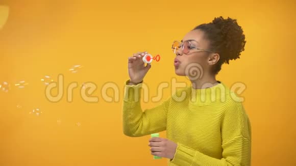 开朗的非裔美国女孩吹肥皂泡玩得开心童年游戏视频的预览图