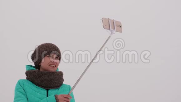 女孩在智能手机和自拍时间上拍照冬天公园慢慢地降雪视频的预览图