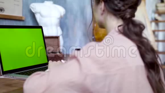 一位年轻女子用绿色屏幕在笔记本电脑上写着一段文字库存录像从事创意的年轻女员工视频的预览图