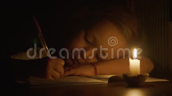 小女孩的特写镜头是在昏暗的房间里用笔在烛光下写的视频的预览图