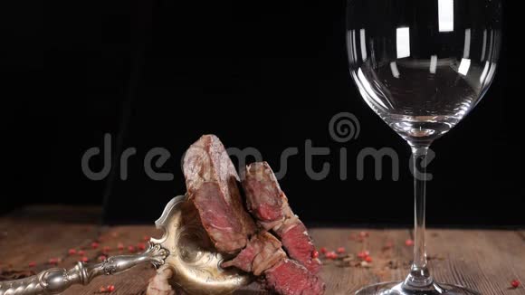 新鲜的熟牛排放在木棕色的木板上红酒缓慢地涌入老式叉子上的肉高清高清视频的预览图