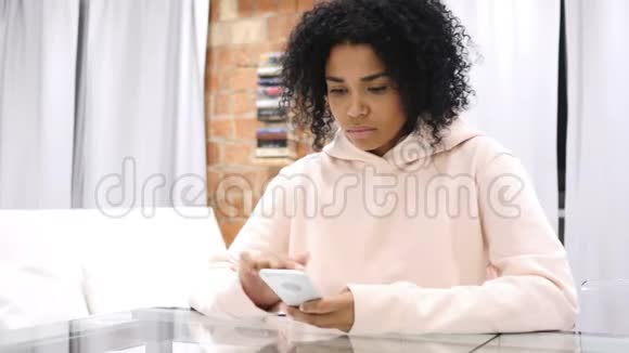 工作中的非裔美国妇女在办公室浏览智能手机视频的预览图