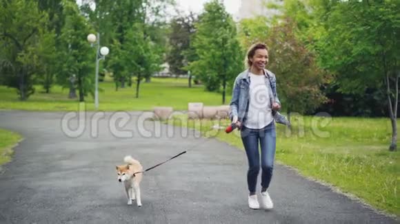 快乐混血女孩在城市公园里与美丽的小狗一起慢跑享受自然自由和户外视频的预览图