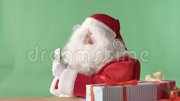 满足的圣诞老人持有美元金钱并显示一个喜欢的标志色彩在背景视频的预览图