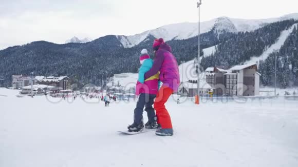 母亲帮助女儿在滑雪坡上正确地骑在滑雪板上寒假概念视频的预览图