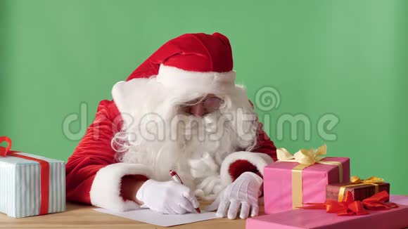 有趣的圣诞老人写了一封信看着相机挥动他的手问候的标志色彩在背景中视频的预览图