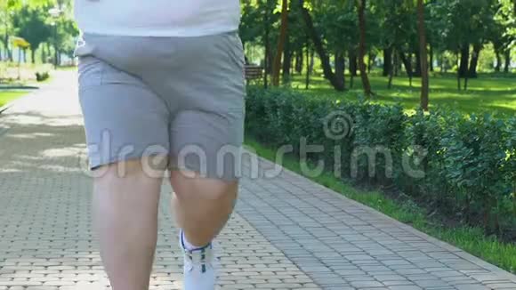 胖子停下来恢复呼吸在公园慢跑与超重作斗争视频的预览图