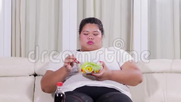 超重的女人在沙发上享受沙拉视频的预览图