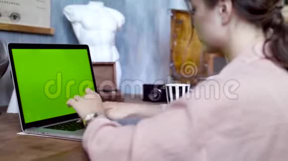 一位年轻女子用绿色屏幕在笔记本电脑上写着一段文字库存录像从事创意的年轻女员工视频的预览图