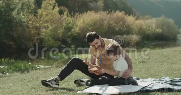 父亲和三岁的儿子在草地上玩耍在一起度过了一段美好的时光视频的预览图