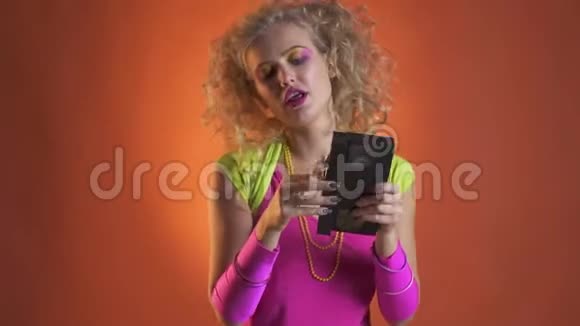 年轻女子穿着五颜六色的复古服装带着古老的盒式磁带跳舞视频的预览图