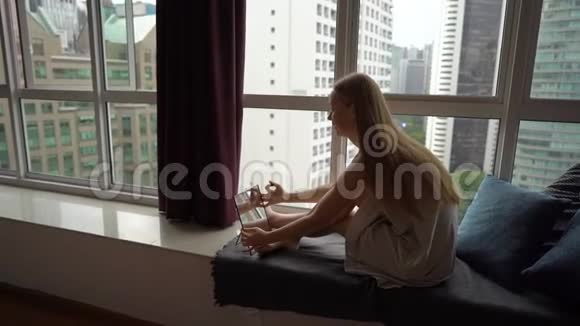 一位年轻女子坐在市区的一扇全景窗旁化妆的超慢动作镜头视频的预览图