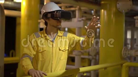 在工业环境石油平台或液化气工厂穿黄色工作服的年轻人使用VR眼镜视频的预览图