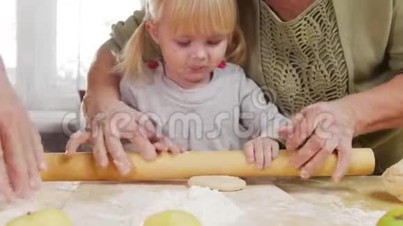 一家人做小馅饼一个小女孩在帮助下擀面团视频的预览图