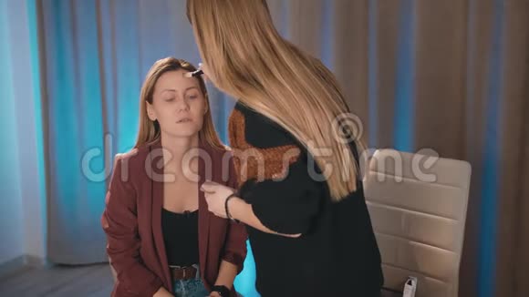 一个化妆师在一个白人金发模特的脸上涂了一把刷子化妆女视频的预览图