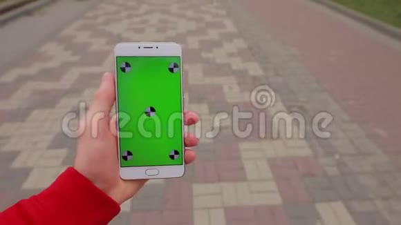 一只雄性手在城市小巷里行走的智能手机空白绿色屏幕视频的预览图