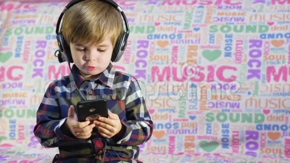 可爱的小男孩在黑色大耳机里听音乐视频的预览图