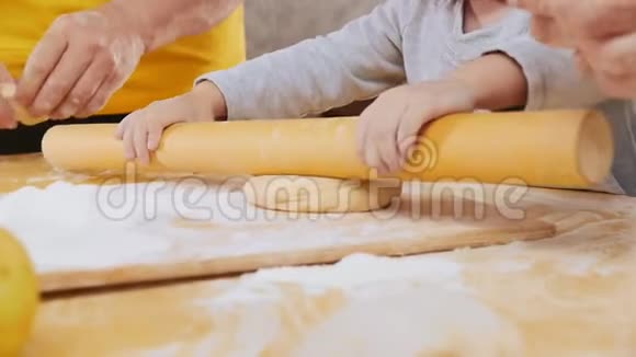 一家人做小馅饼一个小女孩在祖母的帮助下把面团卷出来慢动作视频的预览图