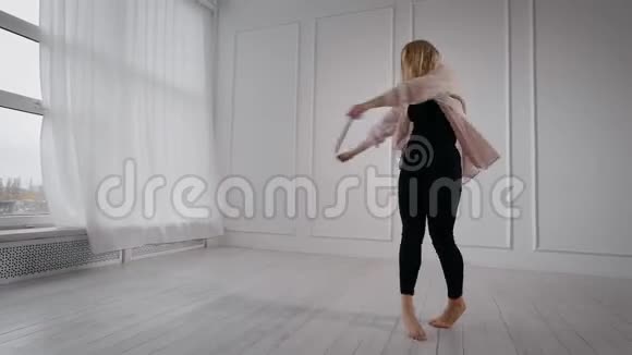 年轻漂亮的金发女郎正在白色的舞厅里排练她的舞蹈表演跳着旋转着视频的预览图