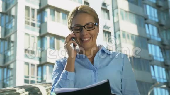 微笑的商务女士在户外谈论智能手机为成功的交易感到高兴视频的预览图