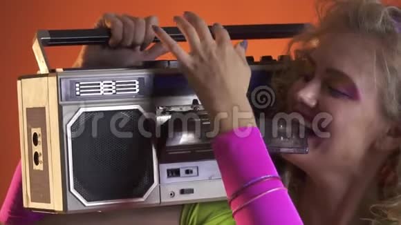 金发女人带着复古的造型把一盒磁带放进老式录音机里视频的预览图