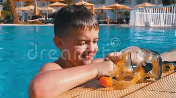 戴着潜水面具的快乐小男孩在埃及酒店的蓝色游泳池里放松视频的预览图