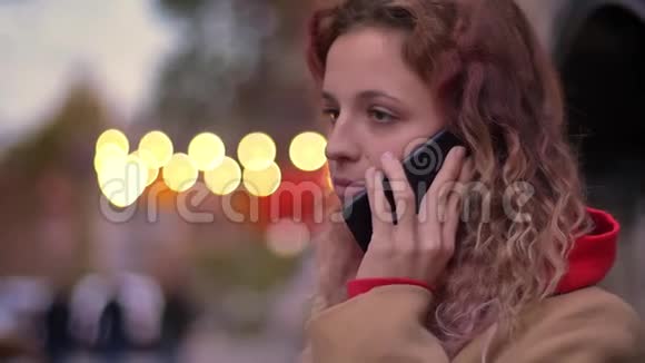 侧面特写照片年轻的金发白种人女孩在模糊的夜晚城市背景上通过手机交谈视频的预览图