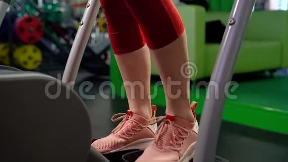 在健身房进行有氧运动时用楼梯踏步机女性腿部的特写视频的预览图