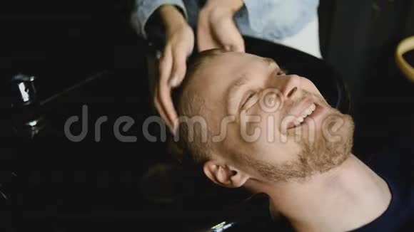 理发师在理发前给一个留胡子的人洗头视频的预览图