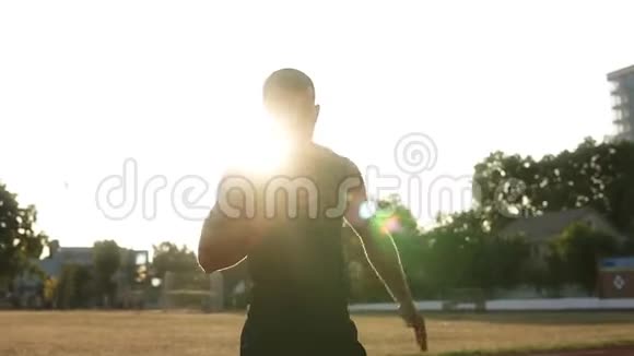 一个肌肉发达的年轻人站在户外体育场挥舞双手热身关节视频的预览图