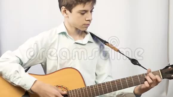 青少年弹声吉他在光墙的背景下视频的预览图