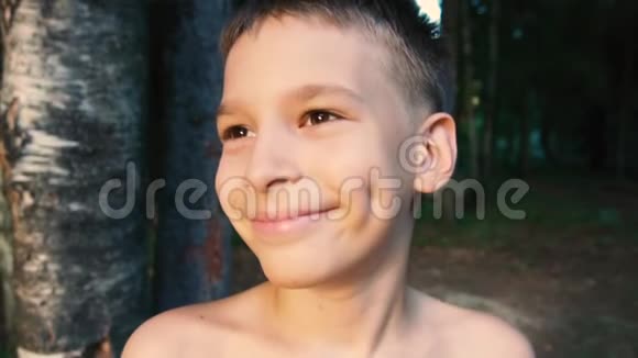 一个男孩正高兴地看着日落在父母家附近的树木中微笑视频的预览图