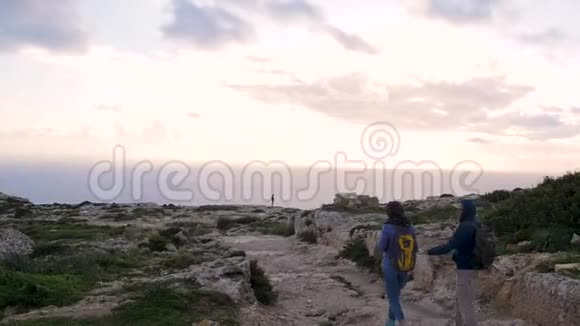 两位游客到悬崖边上看海看日落看神奇的大自然岩石表面视频的预览图