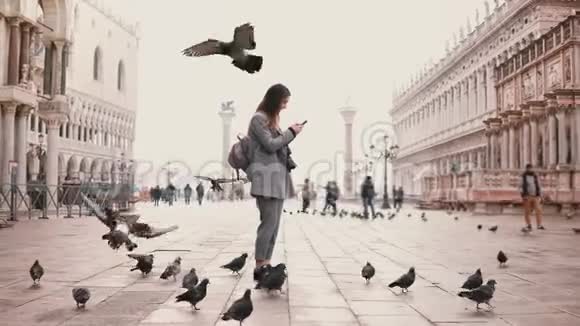 在意大利威尼斯的圣马可广场上一群快乐的女游客在智能手机上拍摄了一张照片照片上到处都是鸟视频的预览图