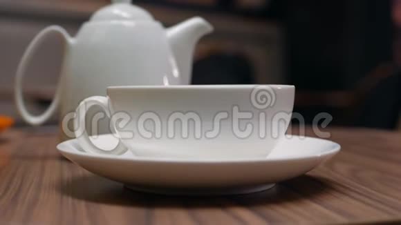 女人的手把茶从咖啡馆的茶壶里倒入一个白色的杯子里特写镜头喝茶4k视频的预览图