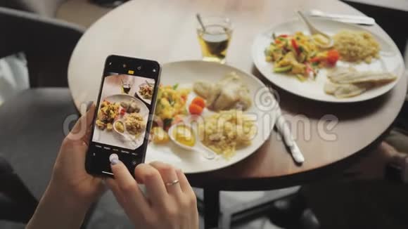 女博主用手机在咖啡馆里拍下她的食物视频的预览图