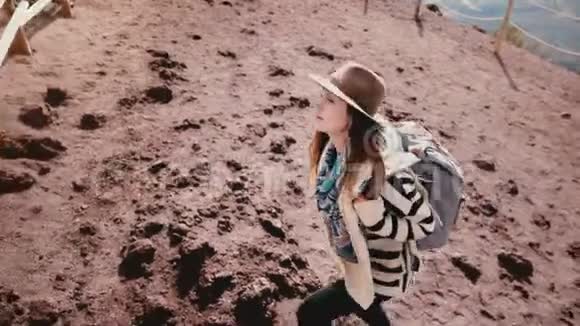 在维苏威火山火山口边缘年轻快乐的女游客的高角度视野背包和手臂张开视频的预览图