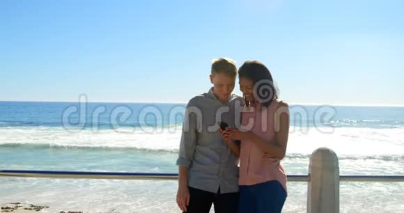 幸福的年轻夫妇在栏杆附近使用手机视频的预览图