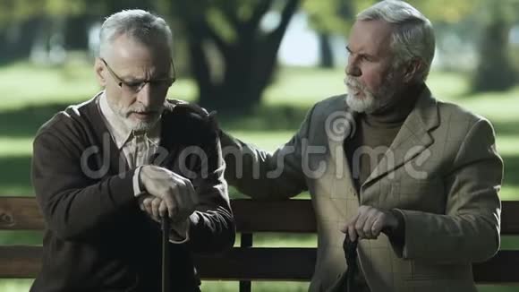 老年男性安慰悲伤的朋友坐在长凳上养老院支持视频的预览图
