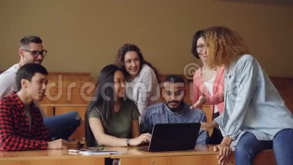 快乐的男人和女人用笔记本电脑看屏幕有说有笑的坐在办公桌前视频的预览图