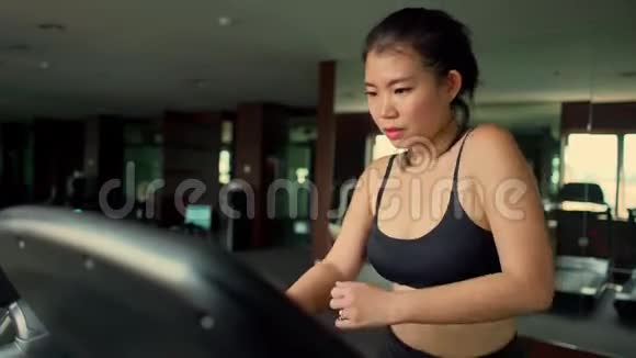 年轻漂亮可爱的亚裔韩国女性在酒店健身房或健身俱乐部进行跑步锻炼在跑步机上慢跑训练视频的预览图