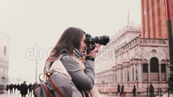 美丽的白种人自由记者带着相机拍摄威尼斯圣马可广场的古建筑视频的预览图