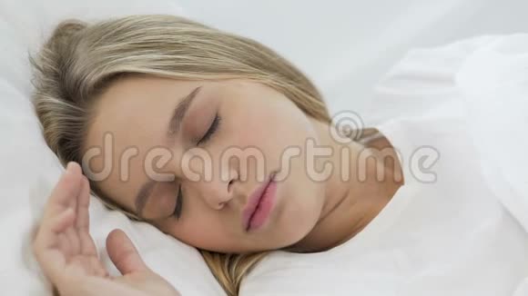 少女在柔软的床单上健康睡眠后在床上伸展特写视频的预览图