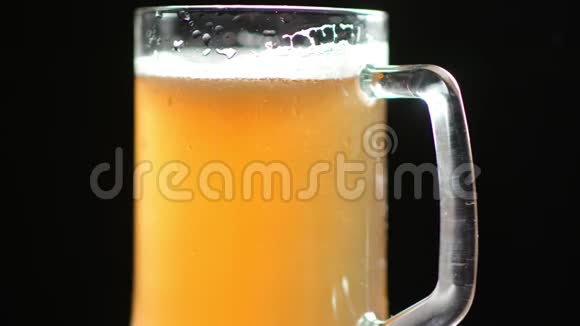 在玻璃杯上盖有水滴的气泡和泡沫的漂亮新鲜啤酒的性能视频的预览图