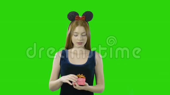 穿着一件连衣裙的快乐女孩手里拿着一件礼物背景是孤立的绿色视频的预览图